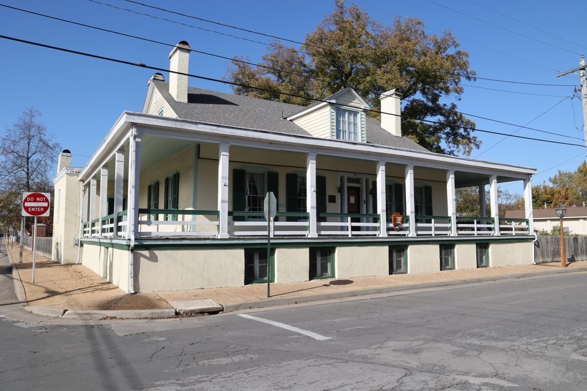 Street view of the two-story cream-colored Jean Baptiste Vallé House with a wraparound porch